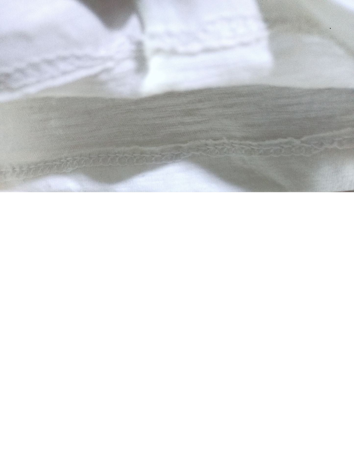 Close-up of white fabric with intricate lace trim.